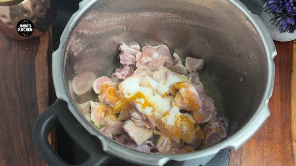 Chicken pieces frying with turmeric powder and salt