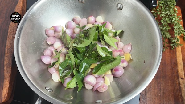 Curry leaves added to sautéed onions for chicken kuzhambu